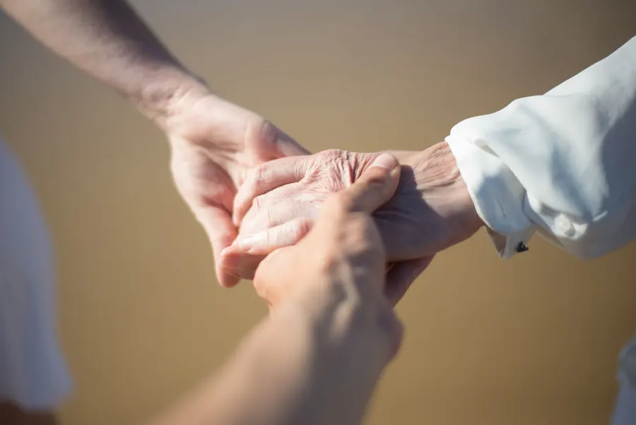 A younger hand gently holding an older person's hand